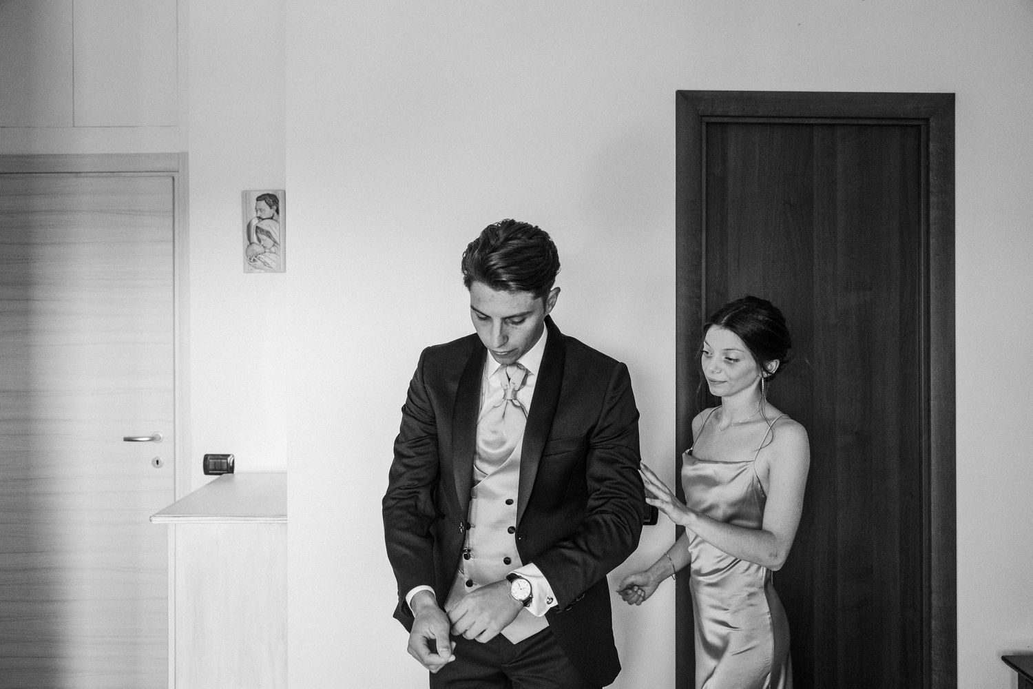 A black and white image showing wedding preparations in an interior doorway.