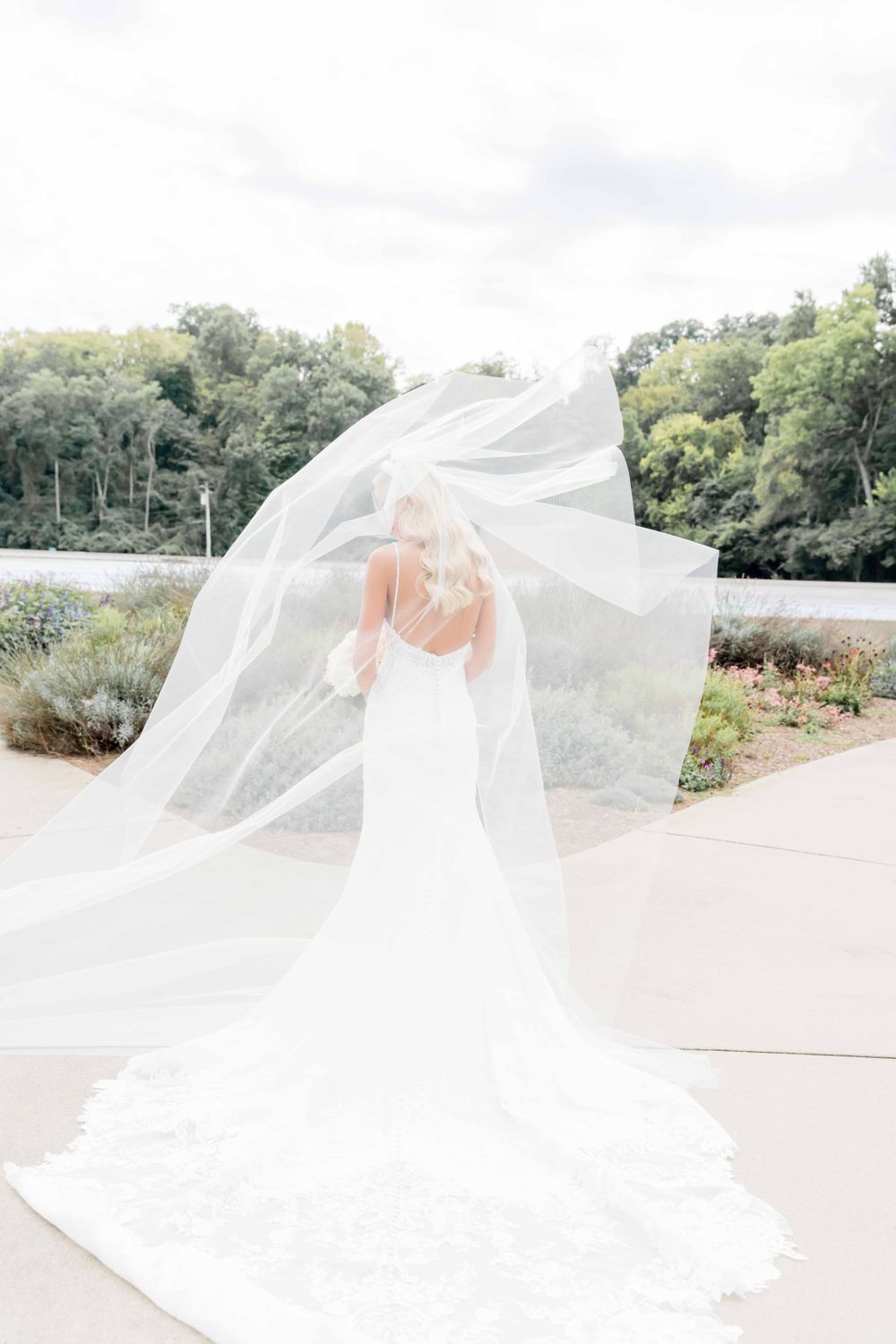 Flowing white wedding veil caught in breeze against natural outdoor backdrop.
