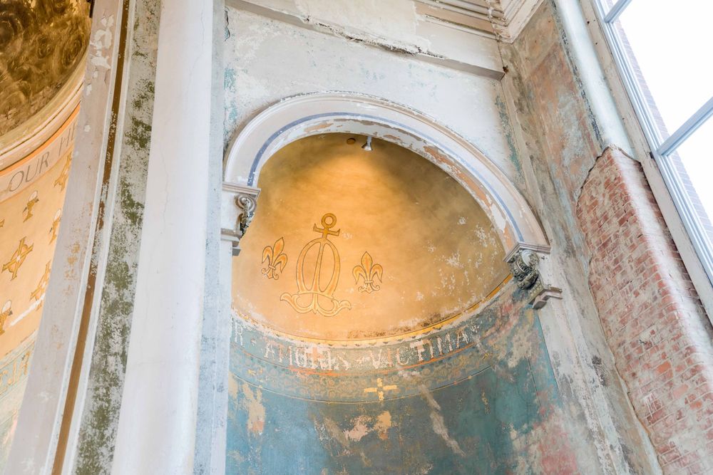 Ornate church interior with detailed arch and faded religious fresco artwork.