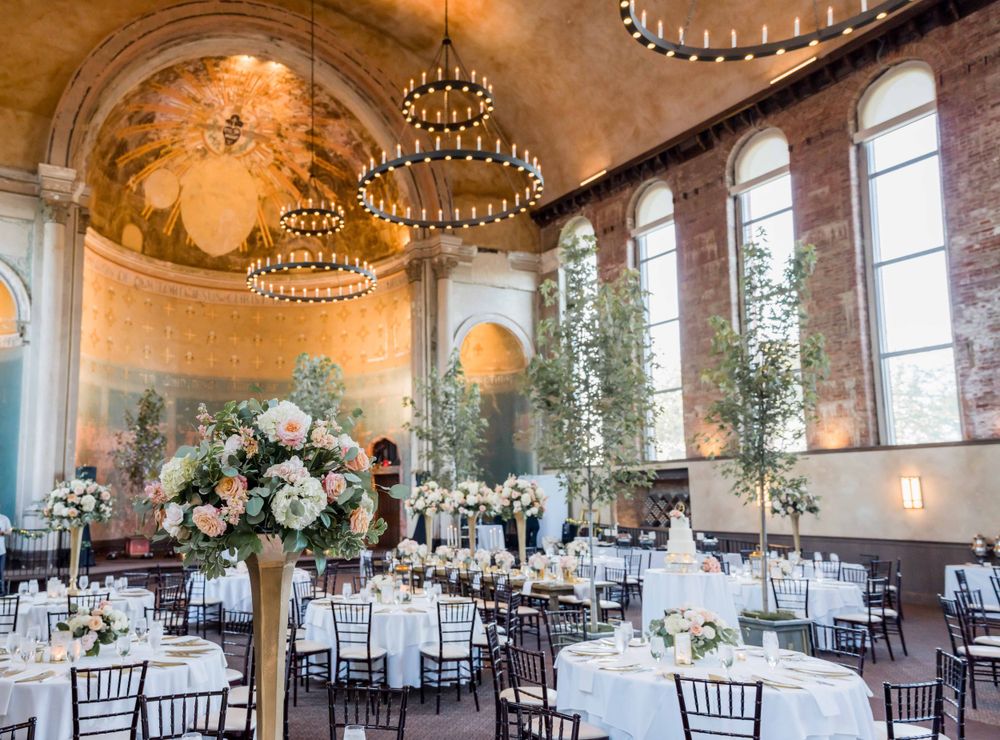 Grand ballroom wedding venue with crystal chandeliers, arched windows, and elegant floral centerpieces.