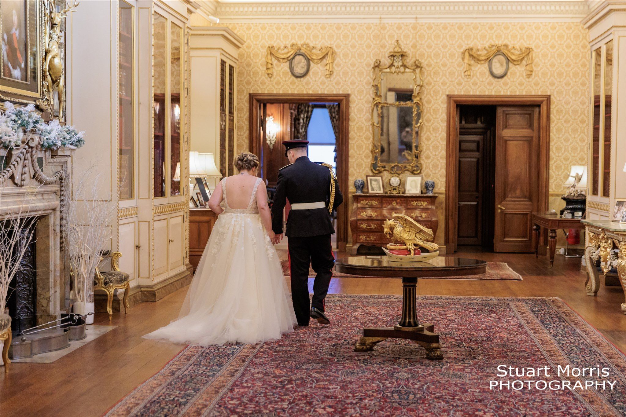 Bride and groom walk through one of the ornate rooms at Knowsley hall Liverpool.