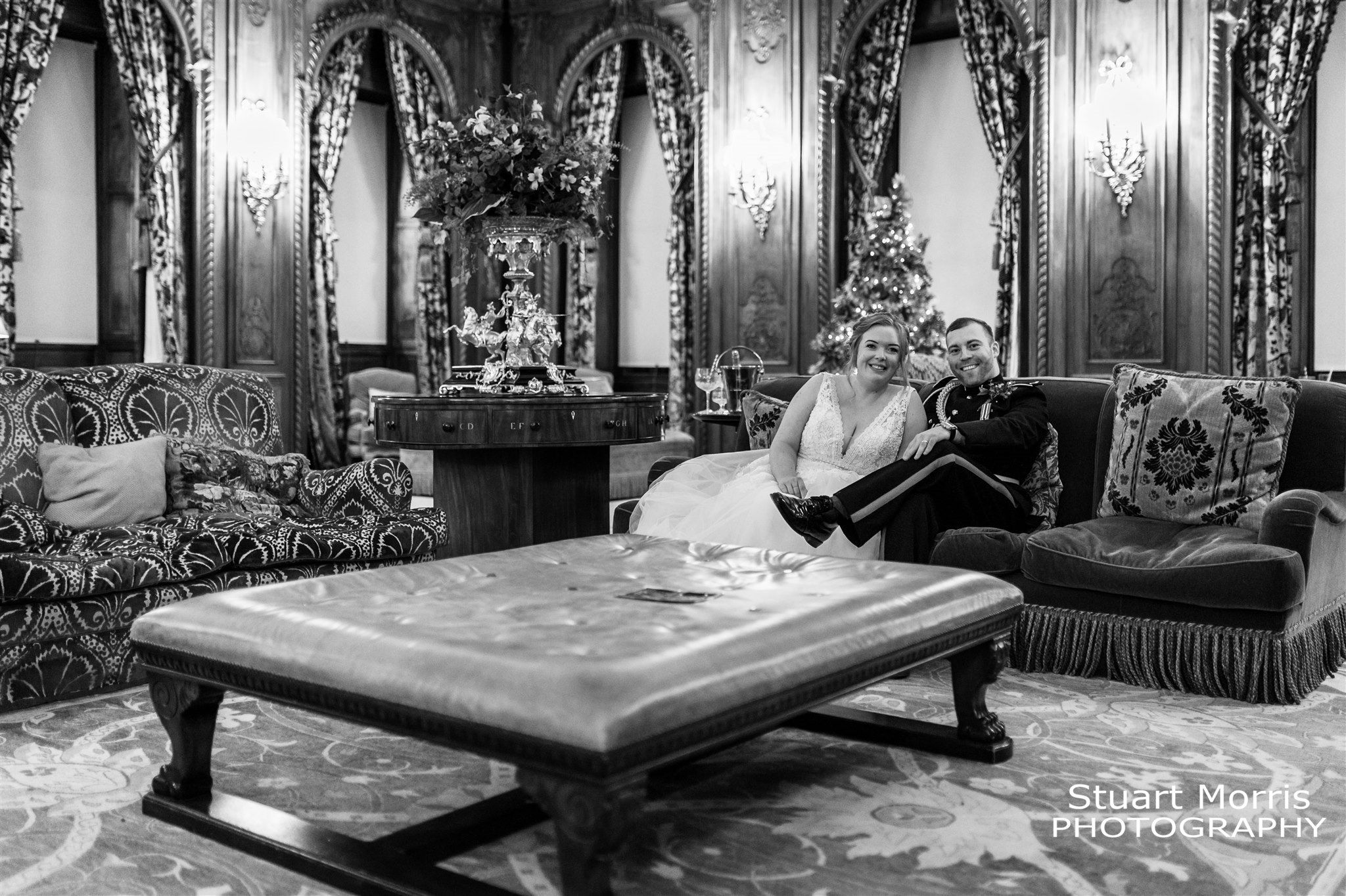 Bride and groom sitting on a leather couch in the sitting room at Knowsley hall Liverpool.