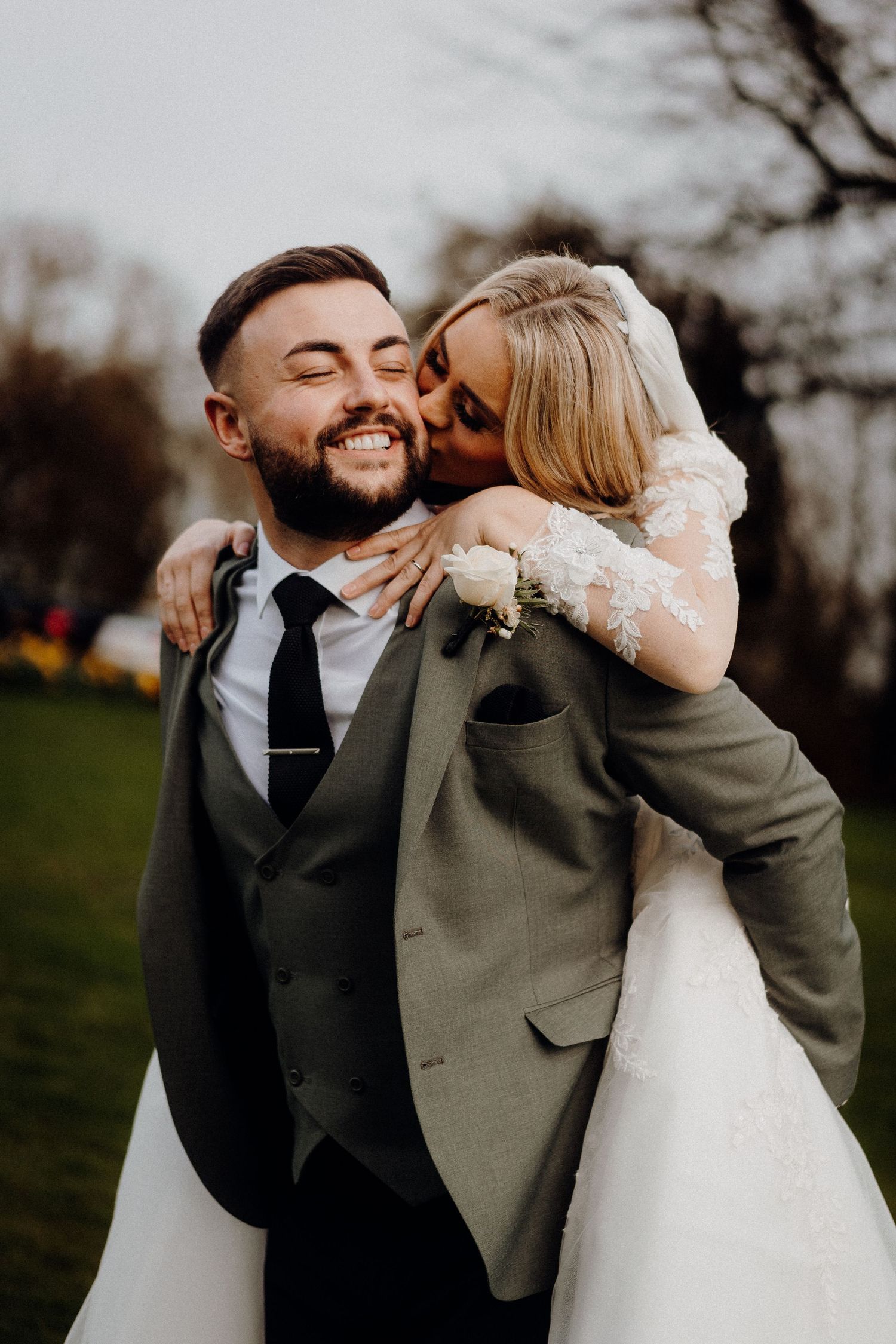 Candid moment of newlyweds embracing and laughing in outdoor setting.