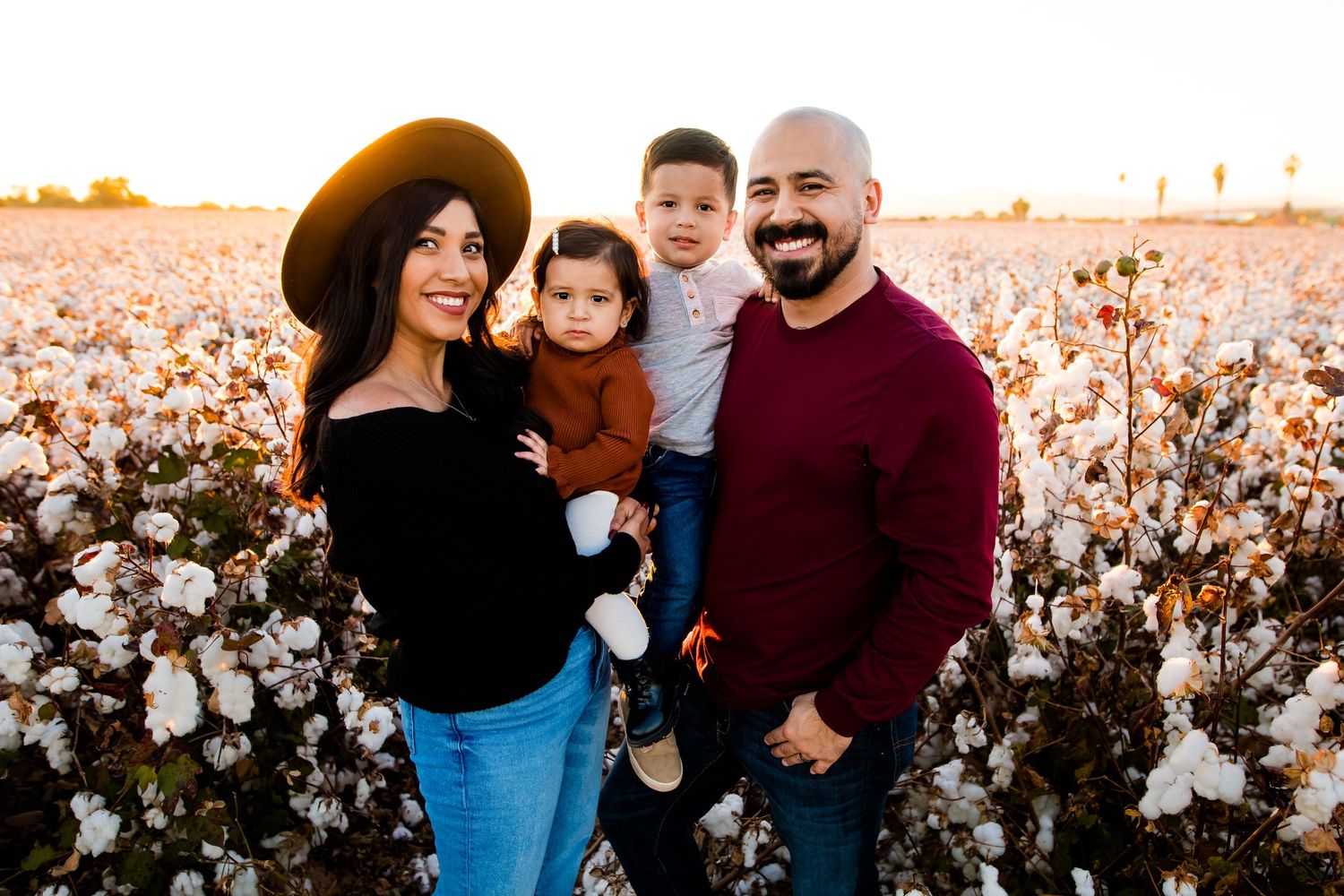 Family poses and smiles in the cotton fields of Arizona at sunset.