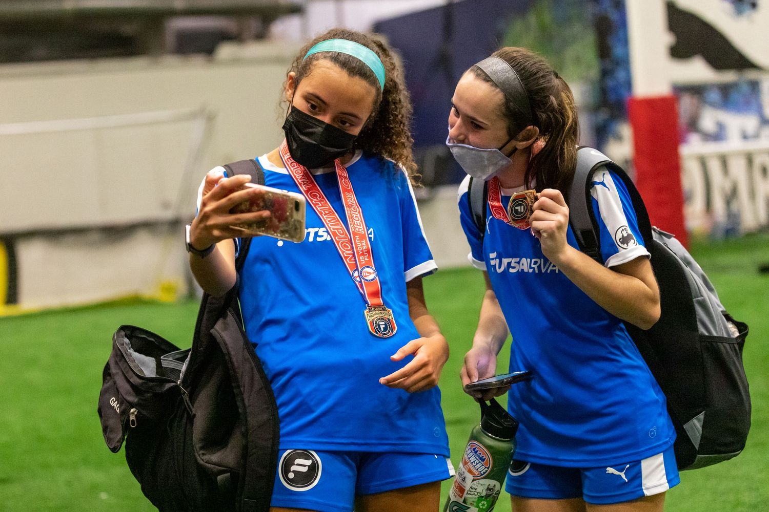 Soccer team members in blue jerseys walking together on grass field.