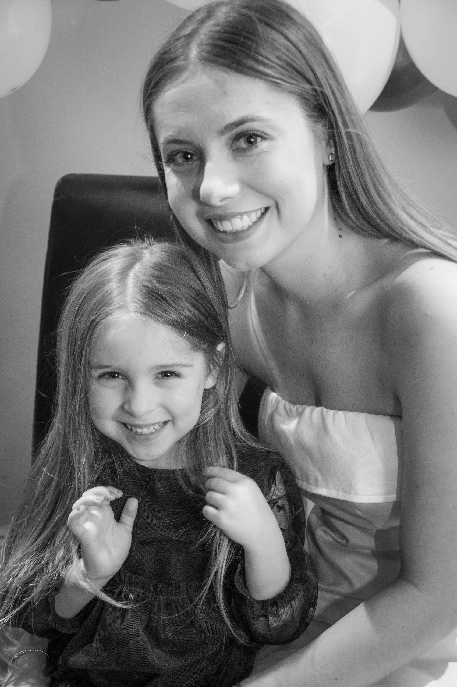 Black and white portrait of two people with balloon decorations behind them.