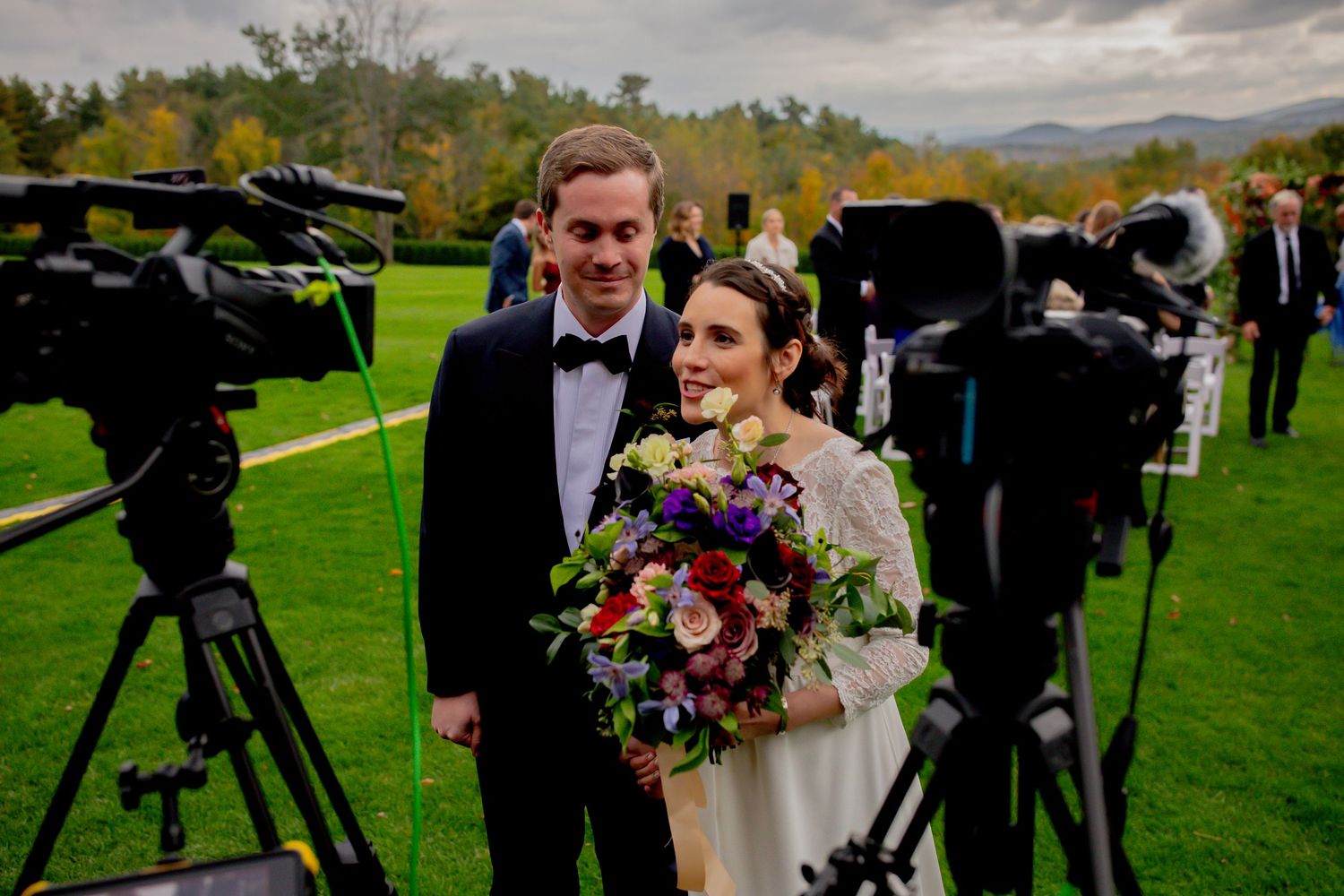 A wedding photoshoot with professional cameras and equipment set up on a green lawn.