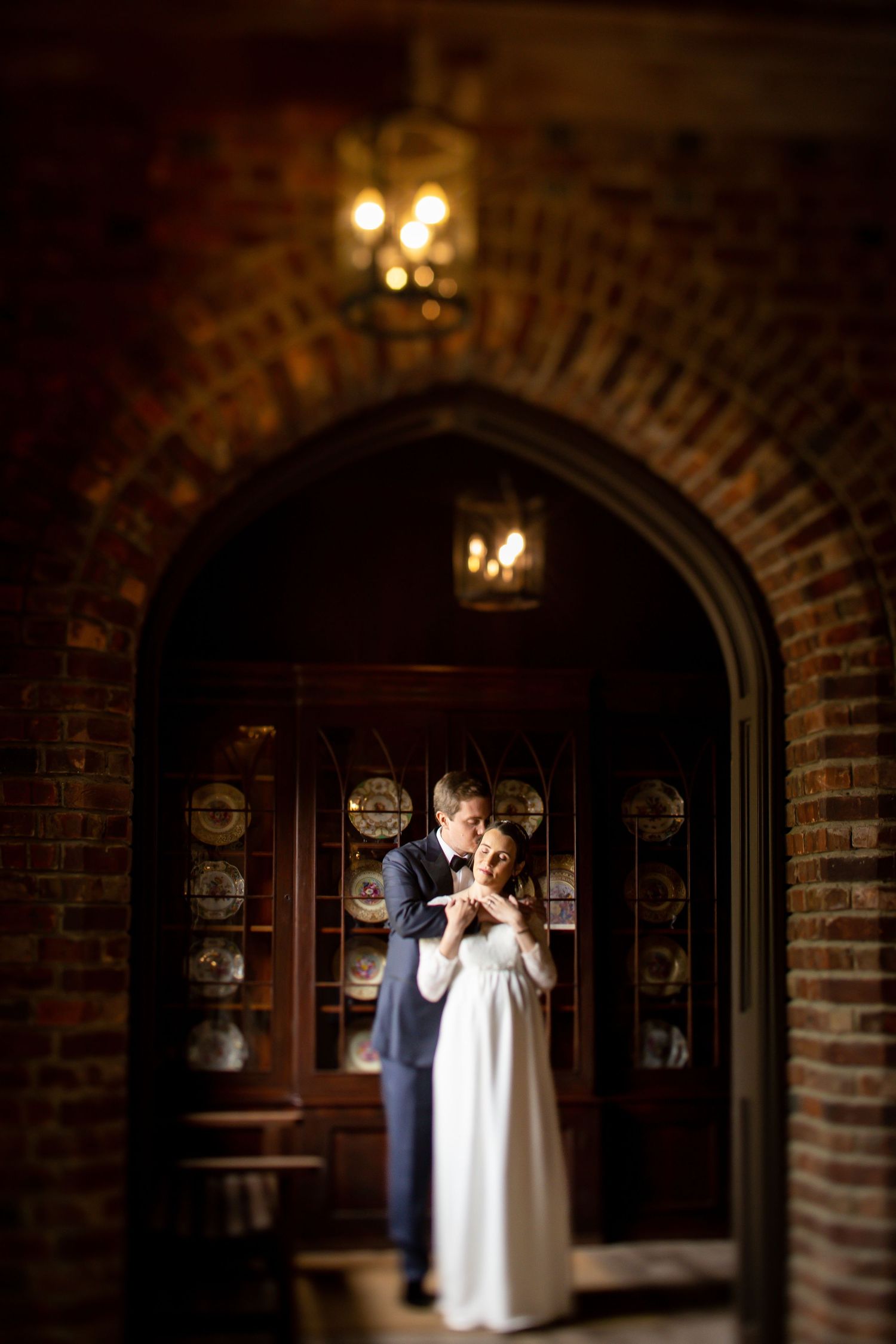 A romantic moment through a brick archway with vintage decor and warm lighting.