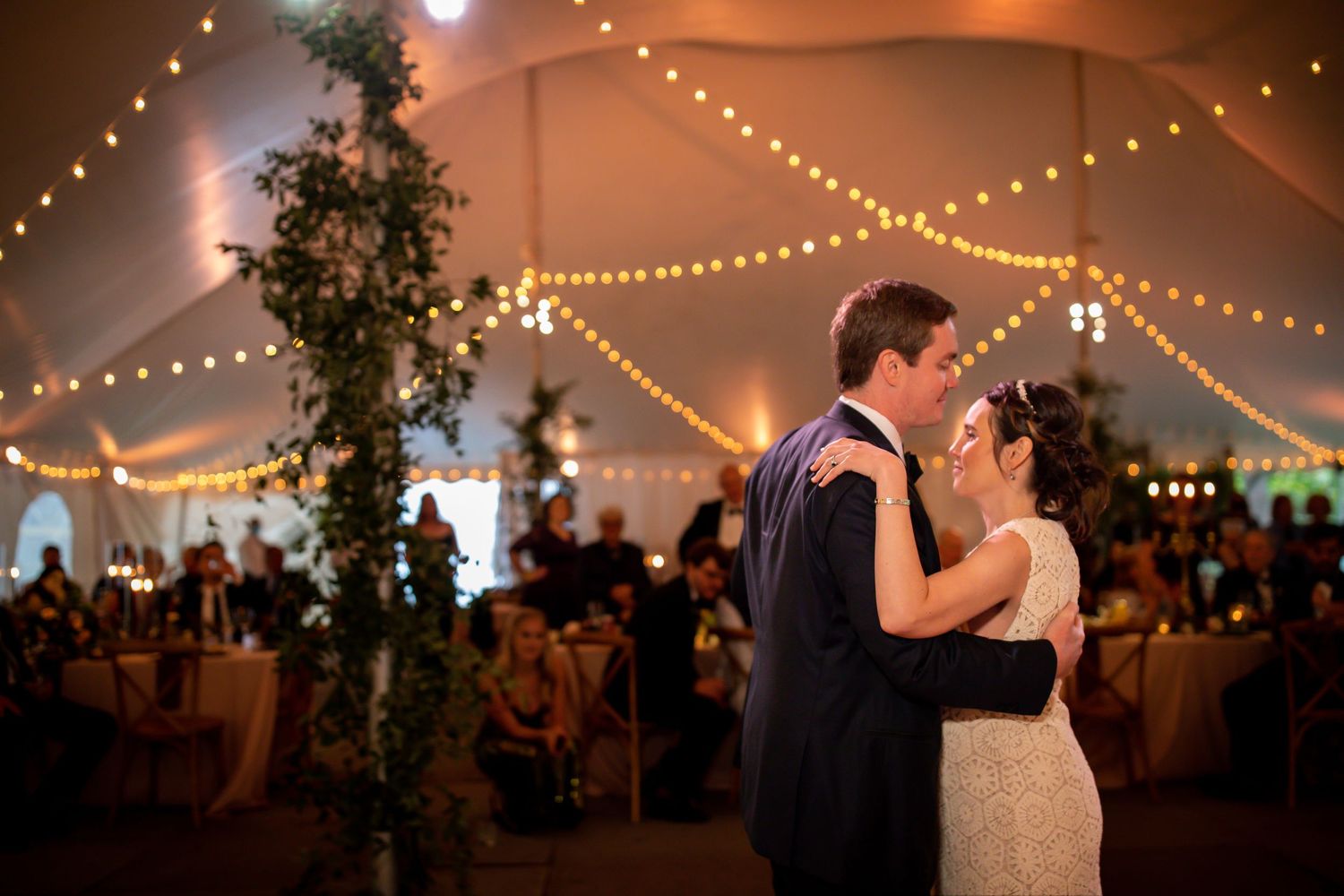 A romantic first dance under twinkling string lights in an elegant reception tent.