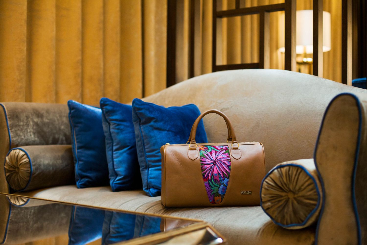 Designer living room featuring brown sofa with blue pillows and floral accent cushion.