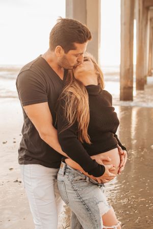 Romantic sunset moment between couple under beach pier.