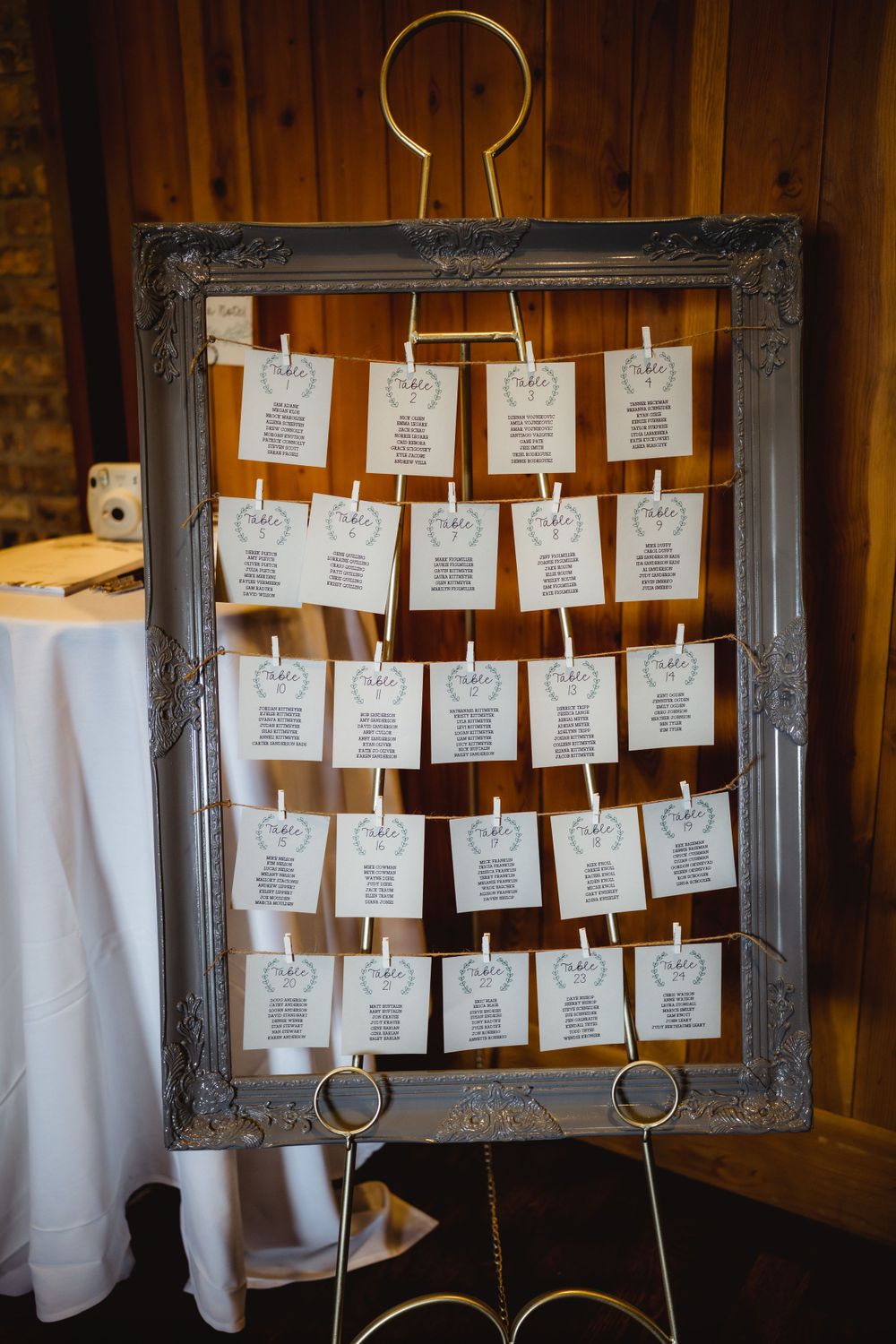 A vintage frame displays wedding seating assignments on small white cards.