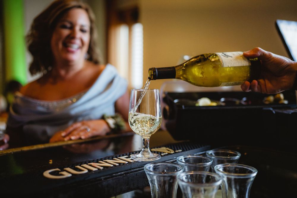 White wine being poured into glasses at an event bar.