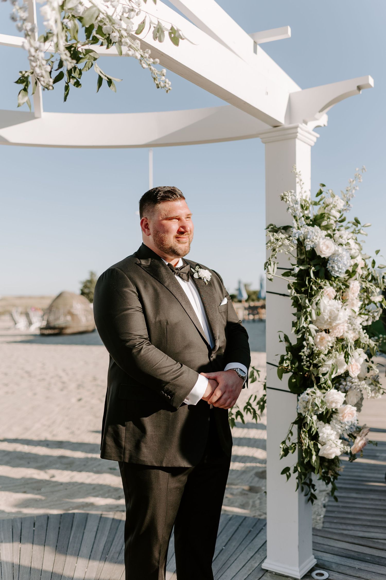 A beachside wedding pergola decorated with elegant white floral arrangements.