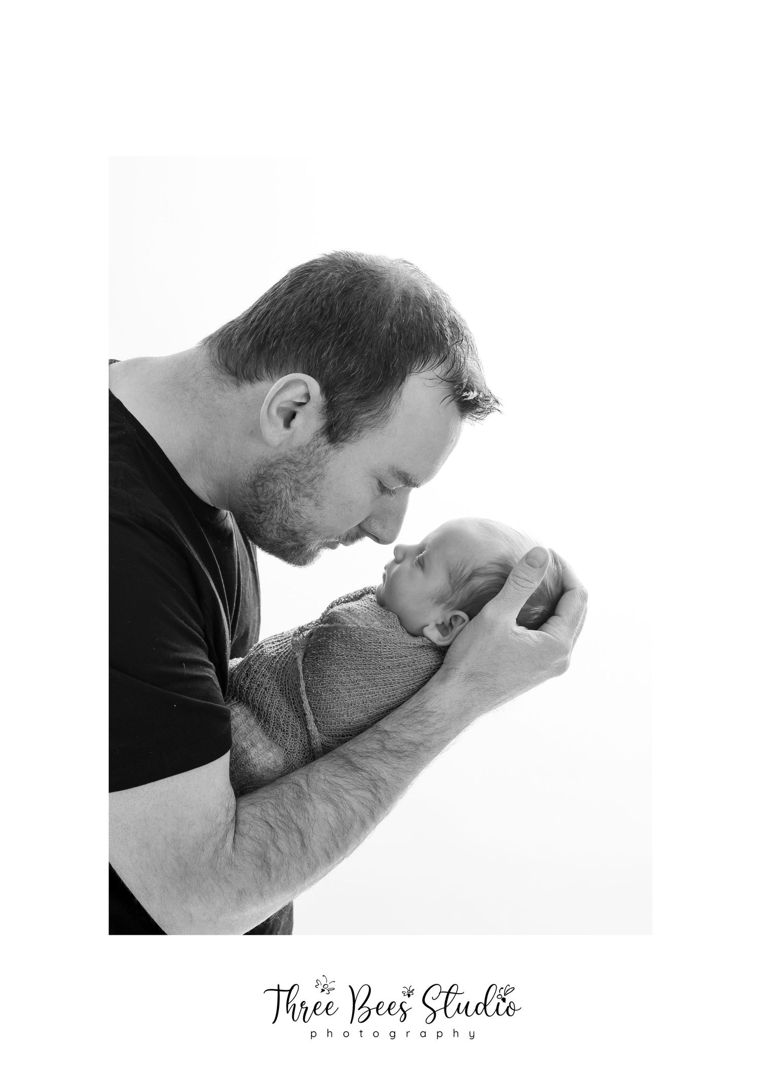 Intimate black and white portrait of parent and newborn baby sharing tender moment against white background.
