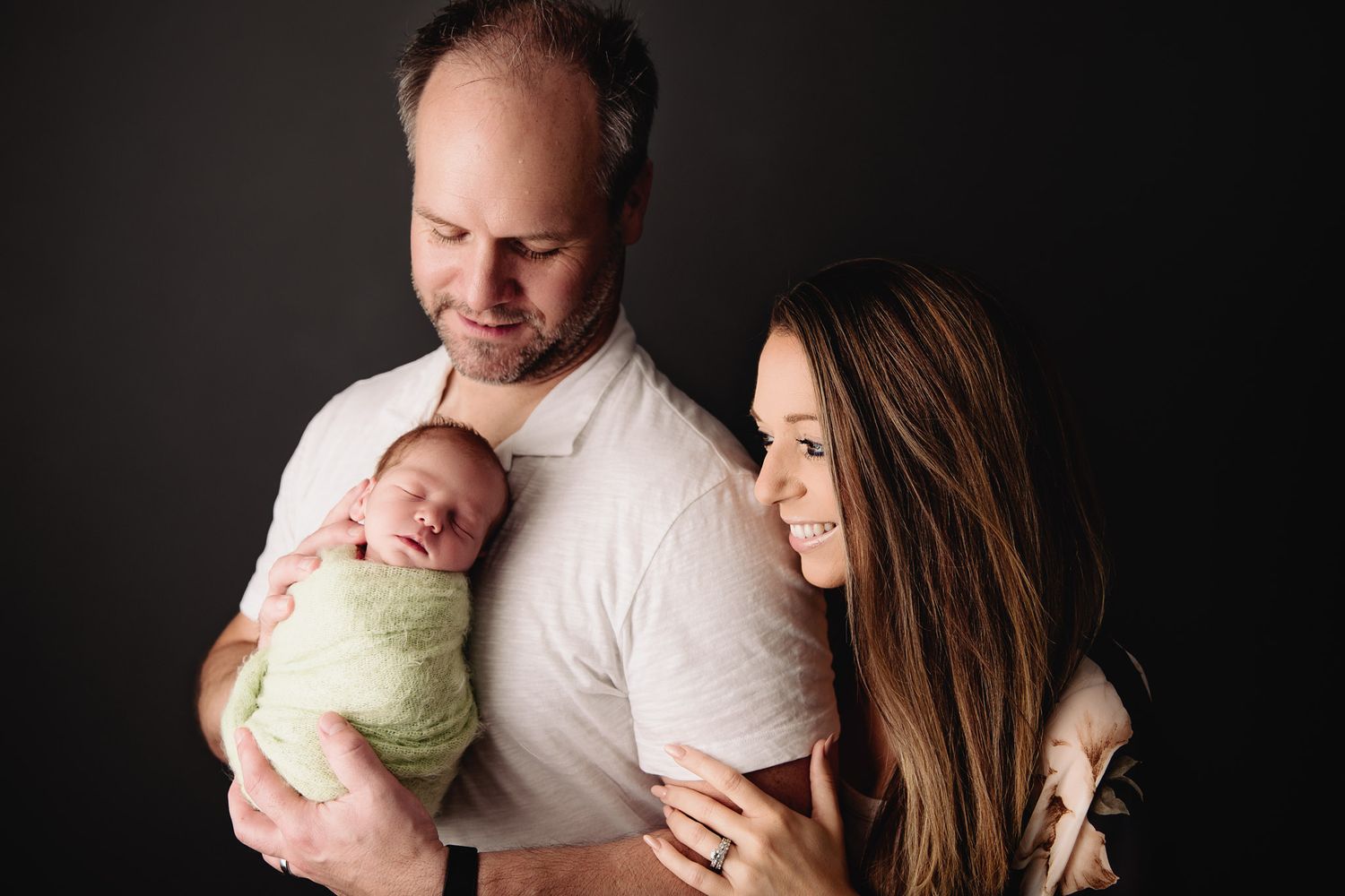father and mother looking at their newborn baby