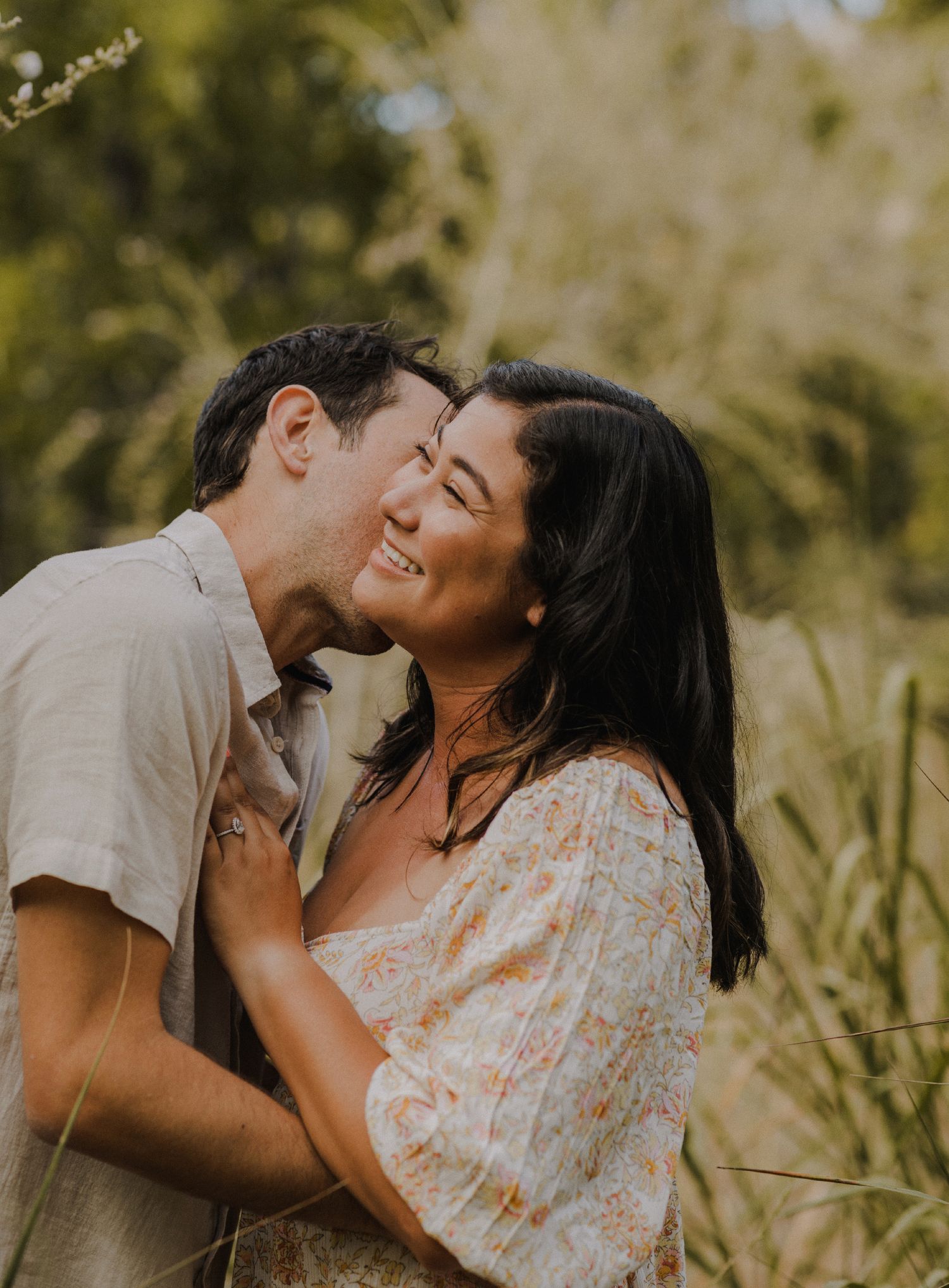 couple laughs candidly while each kissing each other on the cheek