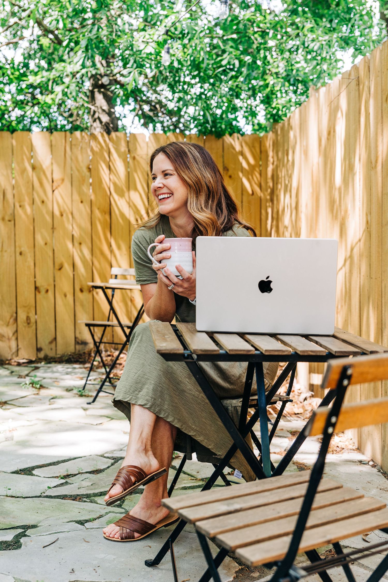 brand photographer sitting outside for her own branding photos with her laptop and coffee at Little Villa Charlotte