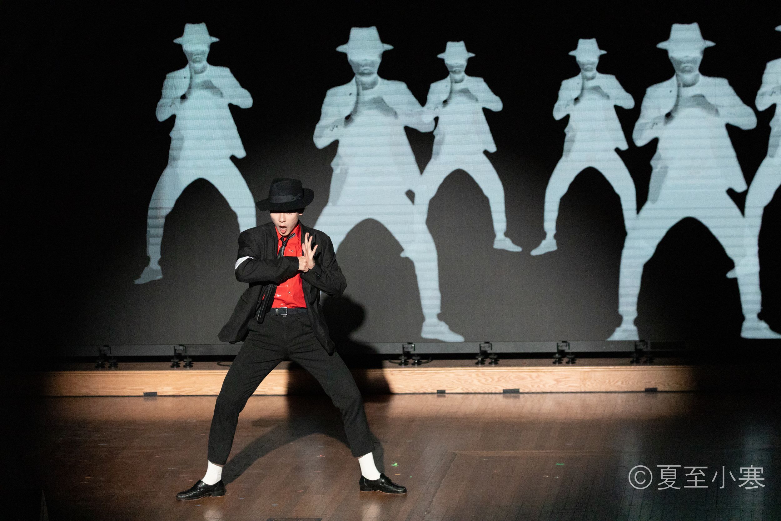 Silhouettes of performers in hats against a light background create dramatic shadow effect.