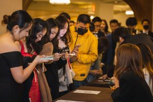 Group of attendees gathered around a registration or check-in table at an event.