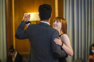 Couple dancing together at formal event with warm lighting in background.