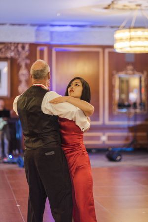 Dance partners perform an elegant ballroom dance move in a warmly lit venue.