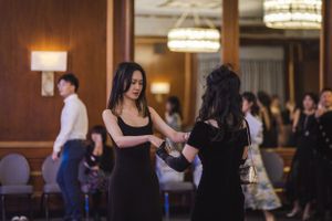 Dancers practice choreography in a grand ballroom with ornate lighting fixtures.