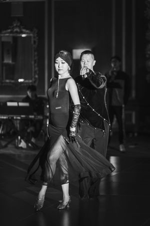 Black and white photo captures dancers mid-performance in formal attire.