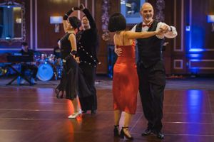 Multiple dance couples perform simultaneously on a polished ballroom floor.