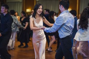 Couples dance together on a wooden floor at an indoor social dance event.