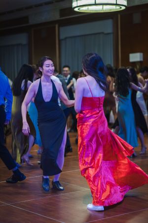 A flowing bright red skirt twirls during a ballroom dance on a dark wooden dance floor.