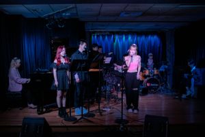 Dark indoor concert venue with performers on stage under blue lighting.