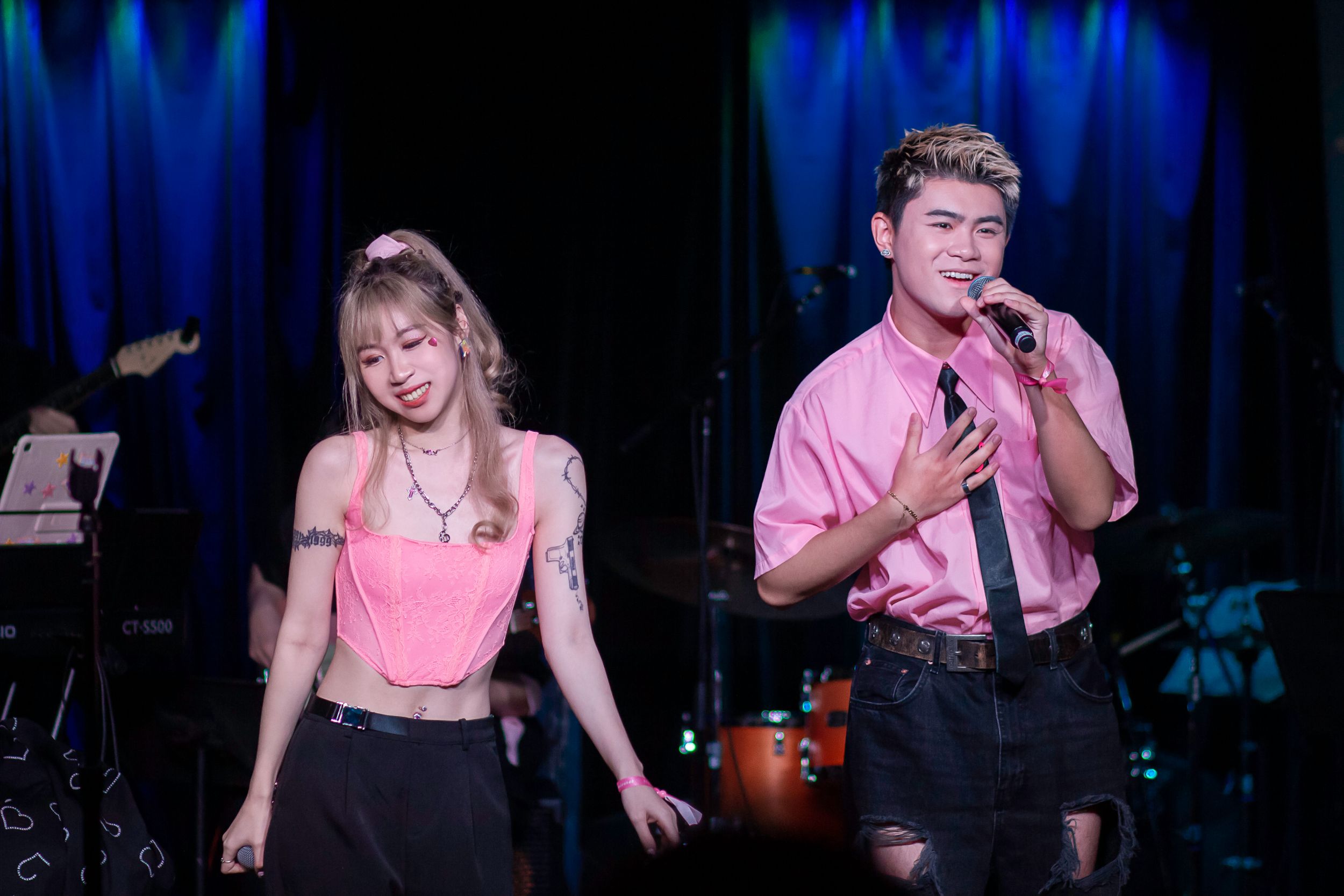 Stage performers in pink and black outfits during a dark theater show.