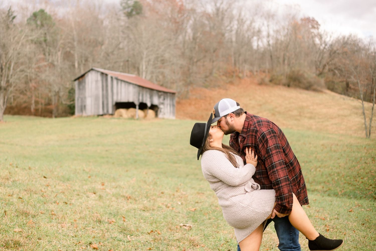 Couple shares romantic moments in a rustic countryside setting.