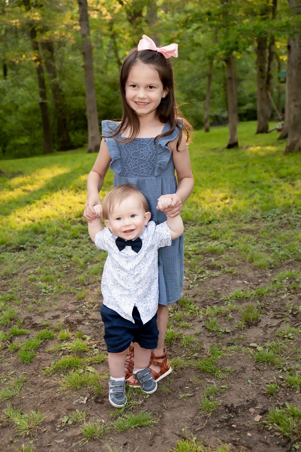 Two siblings share a playful moment together in a forest clearing.