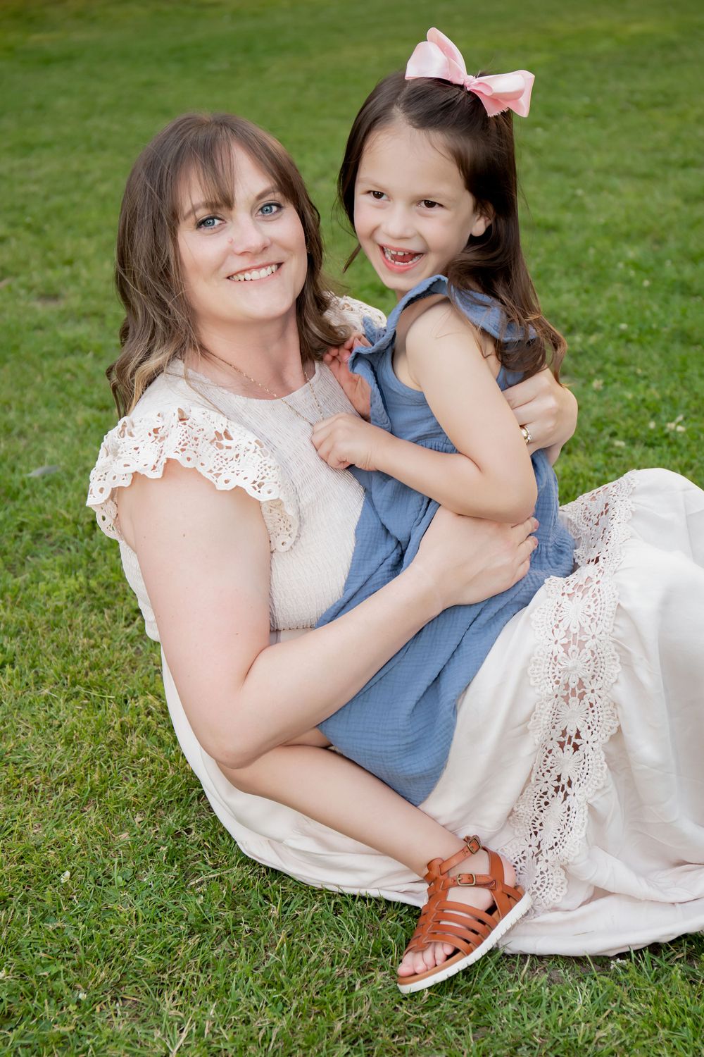 Mother and daughter share a joyful moment together on grass in summer.