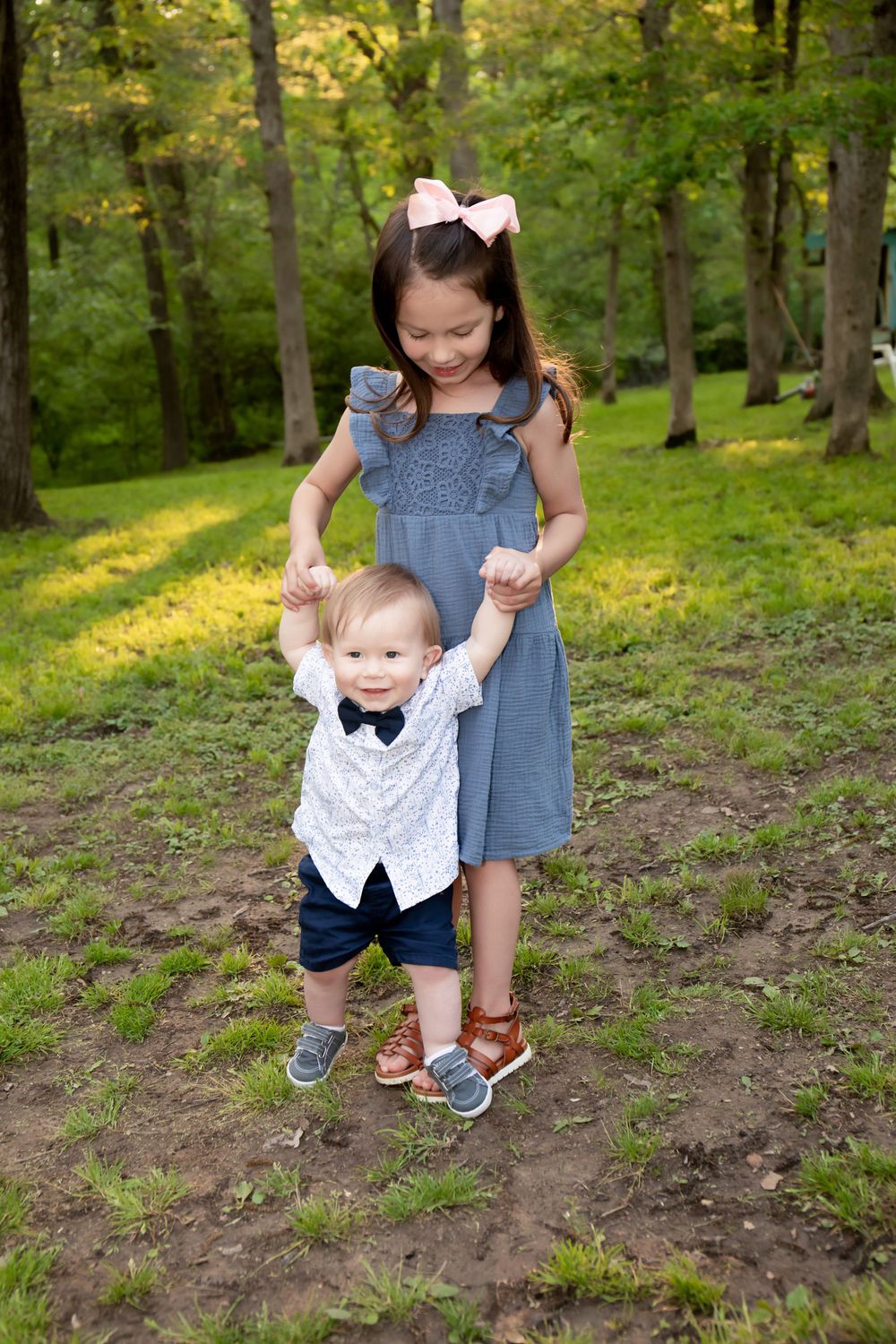 Two children playing together on a wooded path during golden hour.