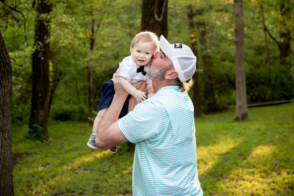 Two people share a joyful moment together in a sunlit wooded area.