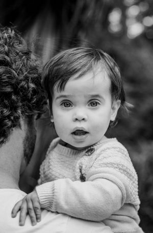A black and white portrait of a baby in a sweater.