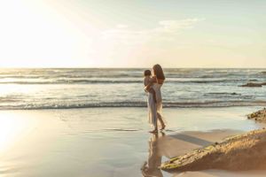 Silhouette figures embrace on beach at golden hour sunset.