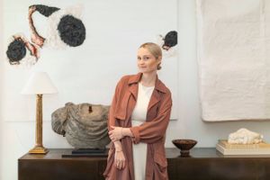 Art gallery space with sculptural pieces and table lamp against white wall.