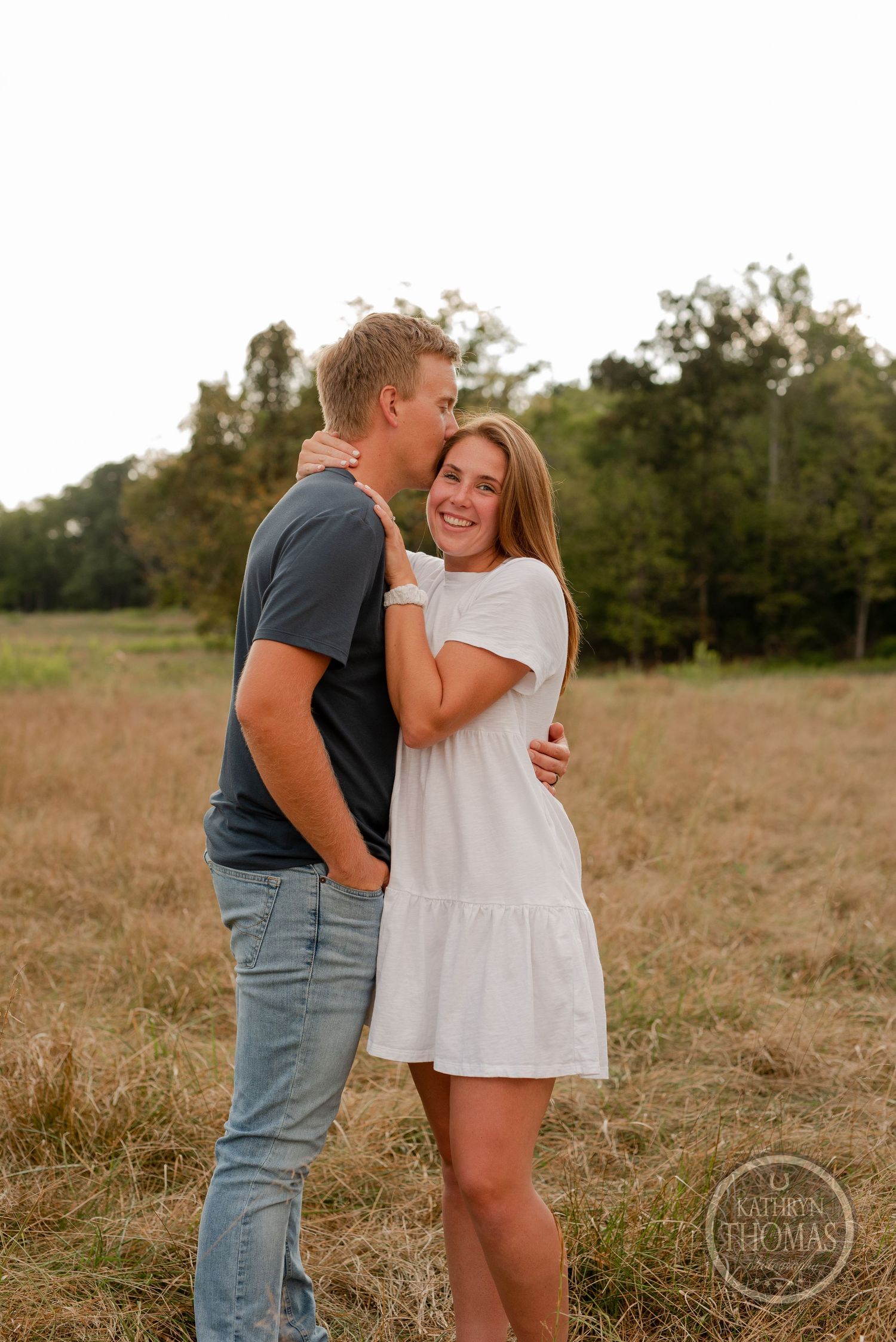 Joyful couple embracing and laughing during countryside photo session.