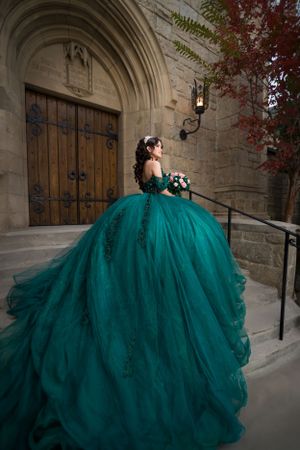 Dramatic emerald ball gown with flowing tulle skirt photographed against gothic church architecture.