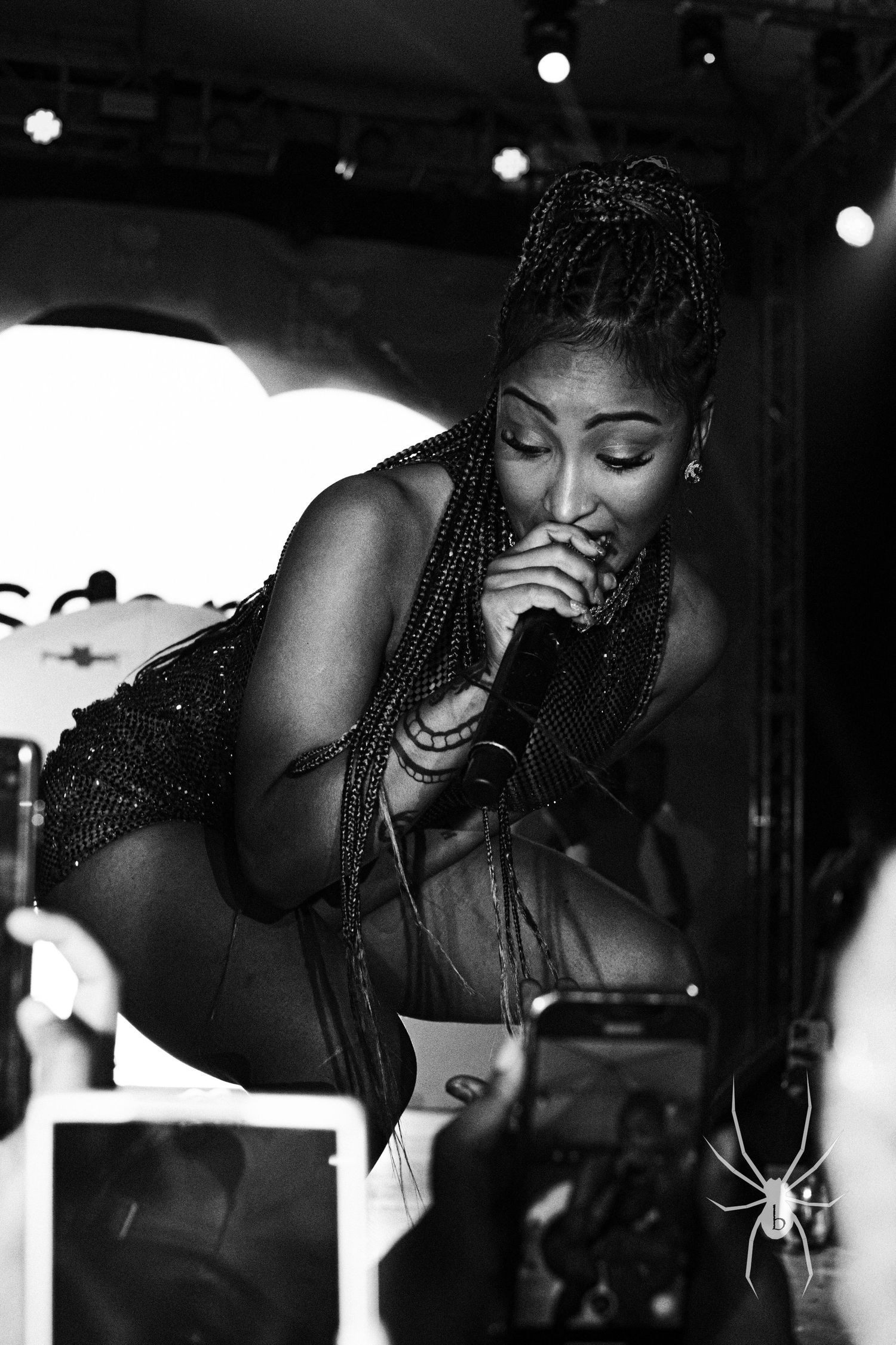 Black and white photo of performer singing emotively on stage in sparkly outfit.