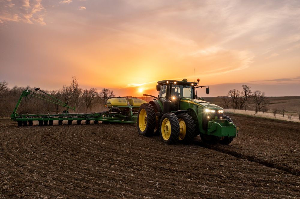 Farmer using a John Deere tractor planting soybeans in an Iowa sunset