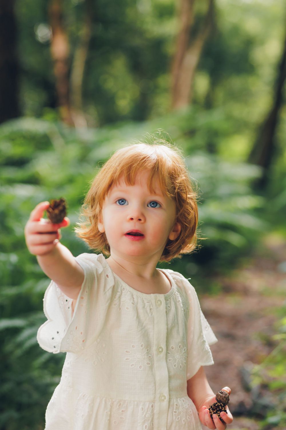 Child in forest with pinecones