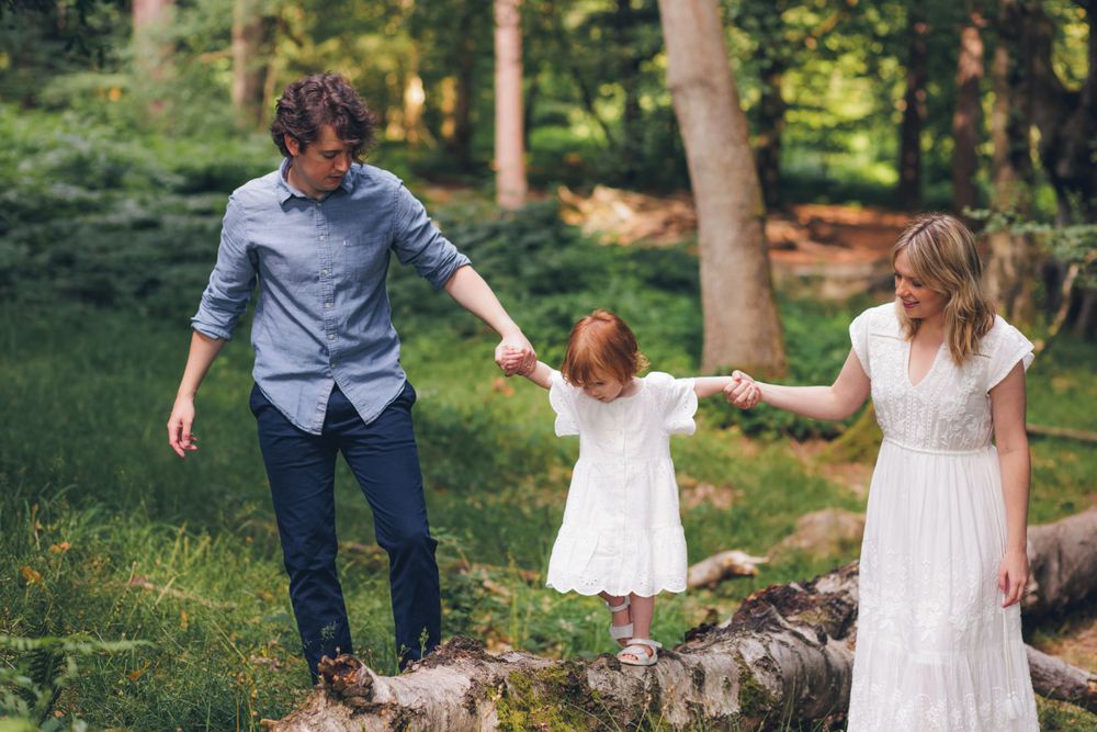 Parents helping child on log