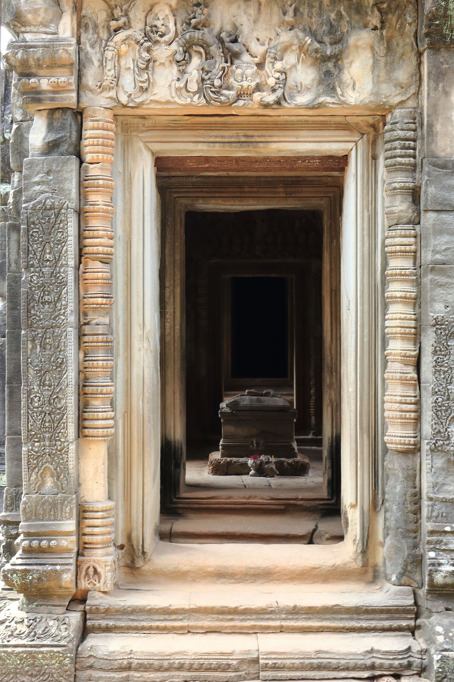 Ornate stone doorway with carved reliefs in an ancient Khmer temple.