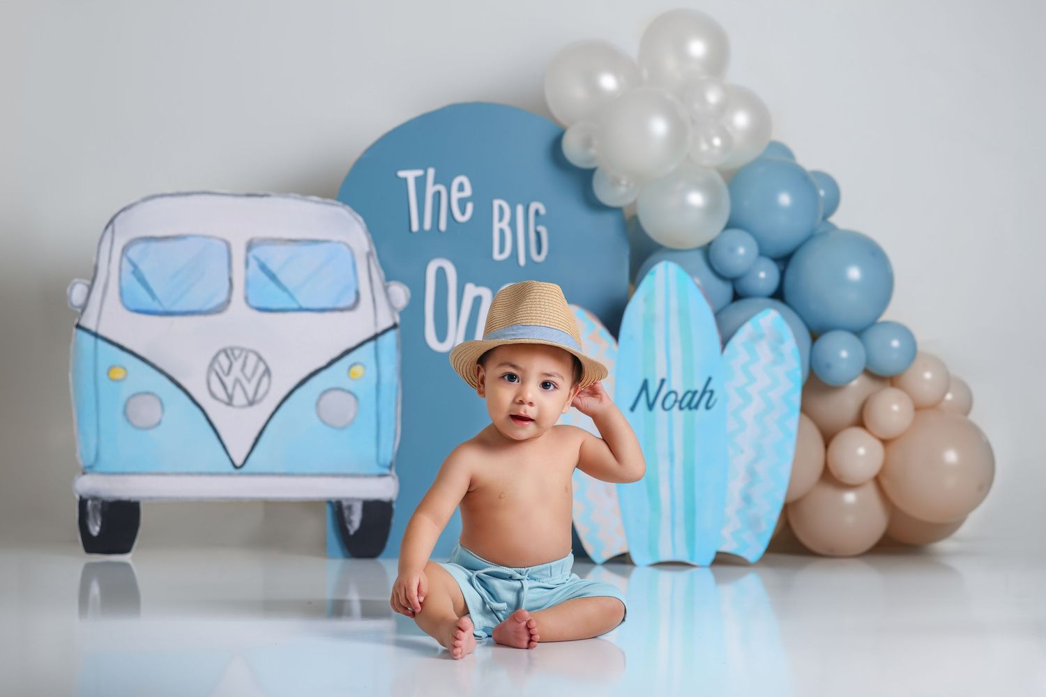 Beach themed birthday setup with blue VW bus cutout and surfboard decorations.