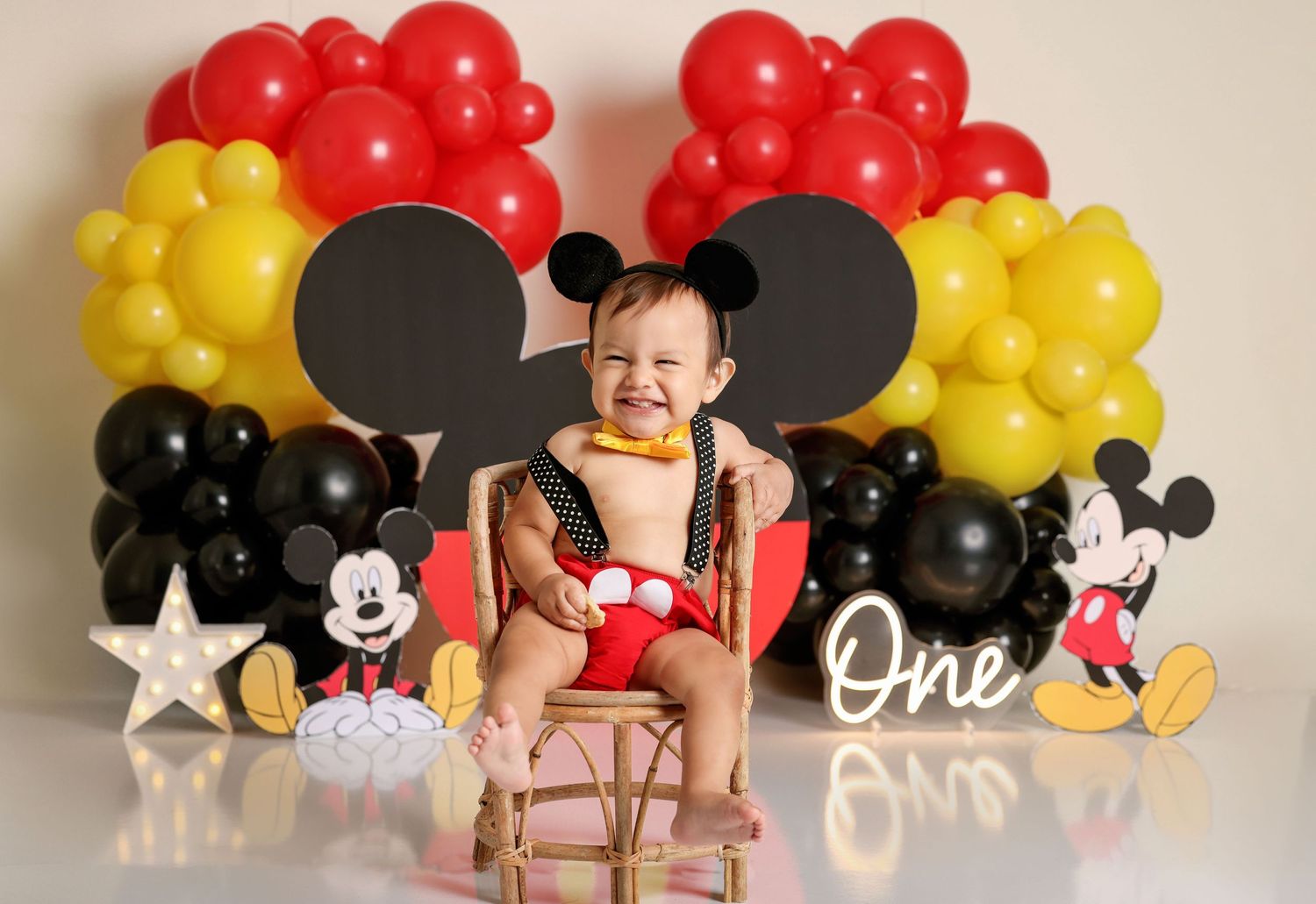 Mickey Mouse themed first birthday setup with balloons in red, yellow and black.